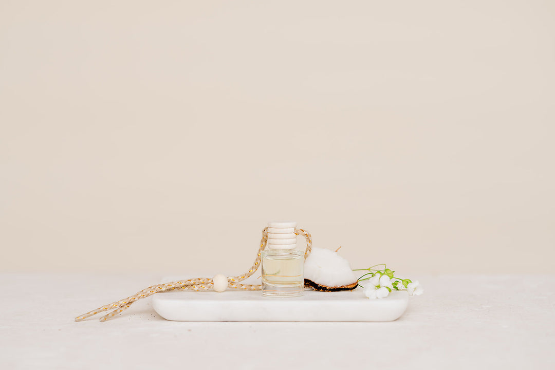 Small glass Car Diffuser bottle on a marble tray against a beige background